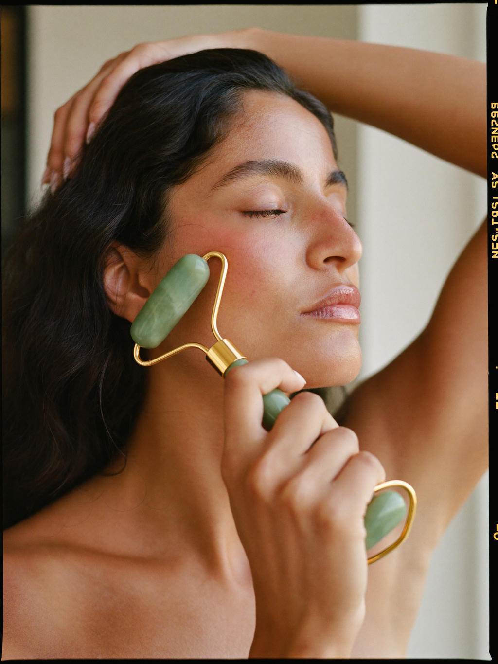 Woman using a jade natural stone facial roller on her cheek
